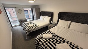 Camera d'albergo con due letti, una finestra vista, un comodino e una lampada a soffitto.