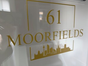 A sign with the number 61 and the name 'MOORFIELDS' in gold lettering, with a silhouette of buildings below. - Cosy Apartment within a short walk to the nightlife and the business district (Liverpool)