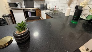 Una cucina moderna con un piano di lavoro nero, elettrodomestici in acciaio inossidabile, mobili in legno e una pianta in vaso.