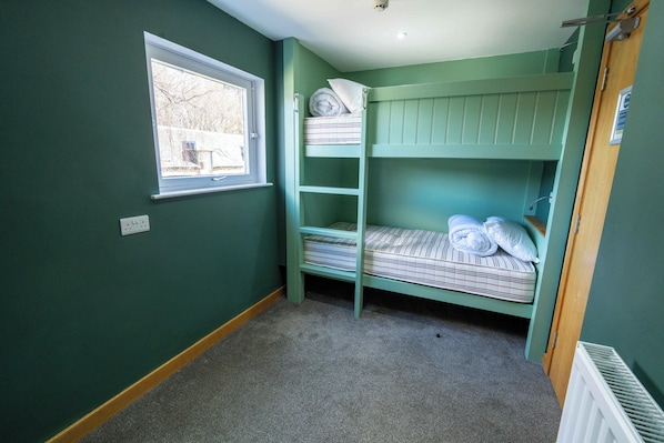 A room with bunk beds, a window, and a radiator.