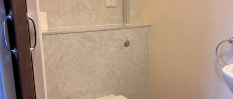 A bathroom with a toilet, a wall-mounted electrical outlet, and a sink.