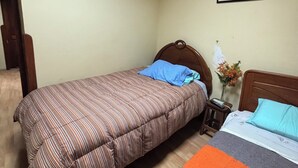 Une chambre à coucher avec un lit, une table de chevet, un tableau encadré au mur et une porte en bois.