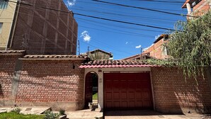 Un bâtiment en briques avec une porte de garage rouge, une allée pavée et un ciel bleu clair.