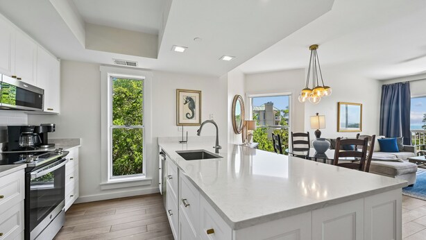 Una cocina moderna con armarios blancos, una isla grande y vistas a zonas verdes.