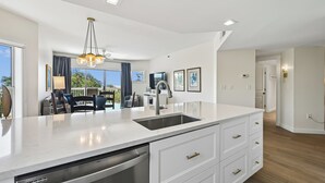 Una cocina moderna con una isla grande, lavavajillas integrado y un comedor con vistas.