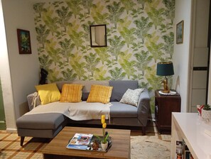 Ein Wohnzimmer mit einer Couch, einem Couchtisch, einer Lampe und einer gemusterten Tapete.