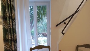 Mesa de comedor dispuesta con platos, cubiertos, una botella roja, una copa y una libreta con una fotografía.