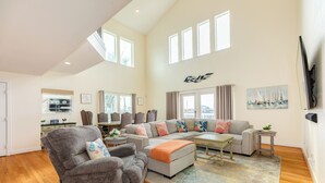 A spacious living area with a sectional sofa, a grey armchair, and a coffee table. - Canal Home w/ 2 Living Areas, 2 Levels of Deck, Hot Tub, Game Room, Pet Friendly (Galveston)