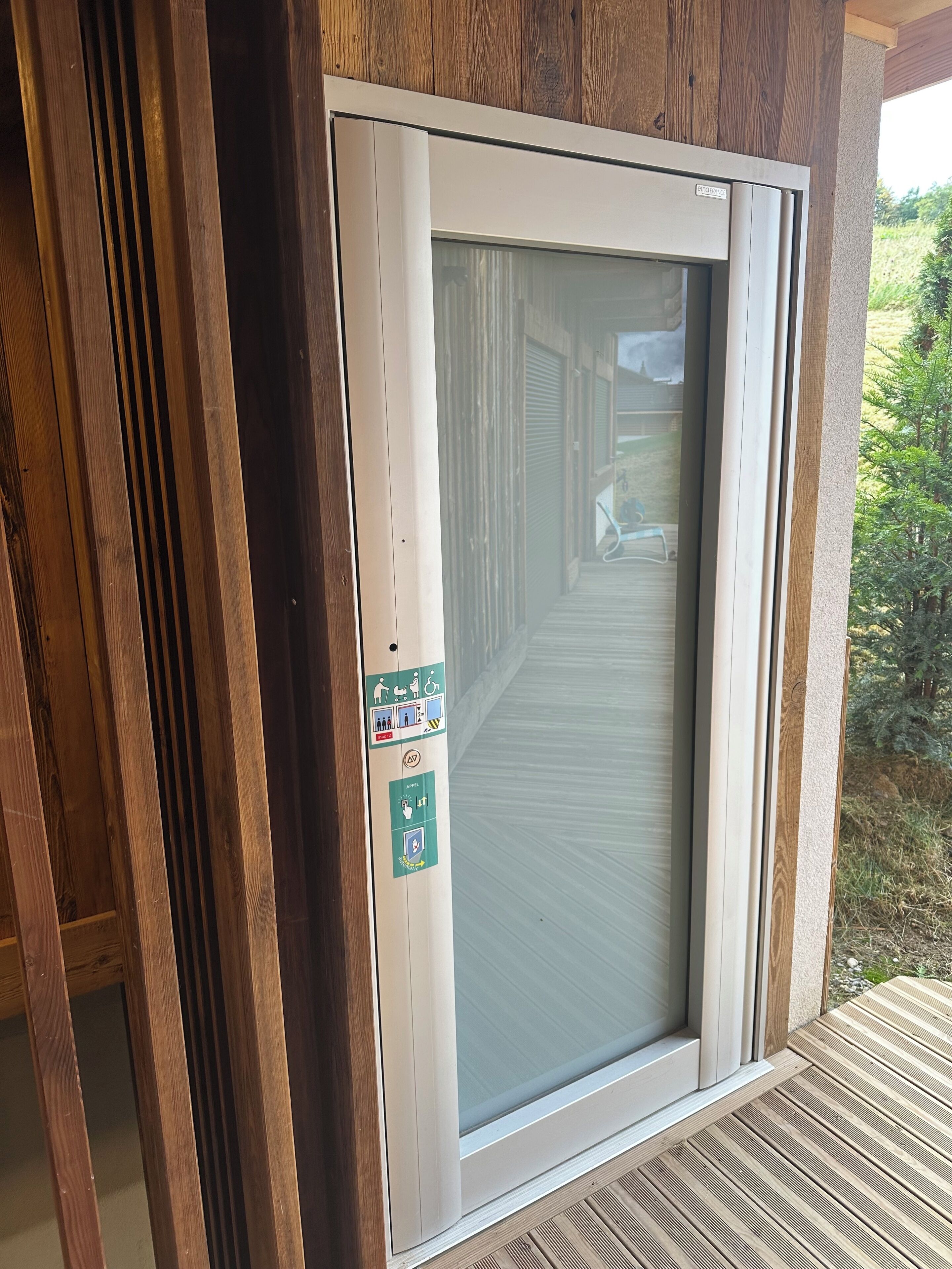 A sliding glass door with a wooden frame and a safety sign attached to it.
