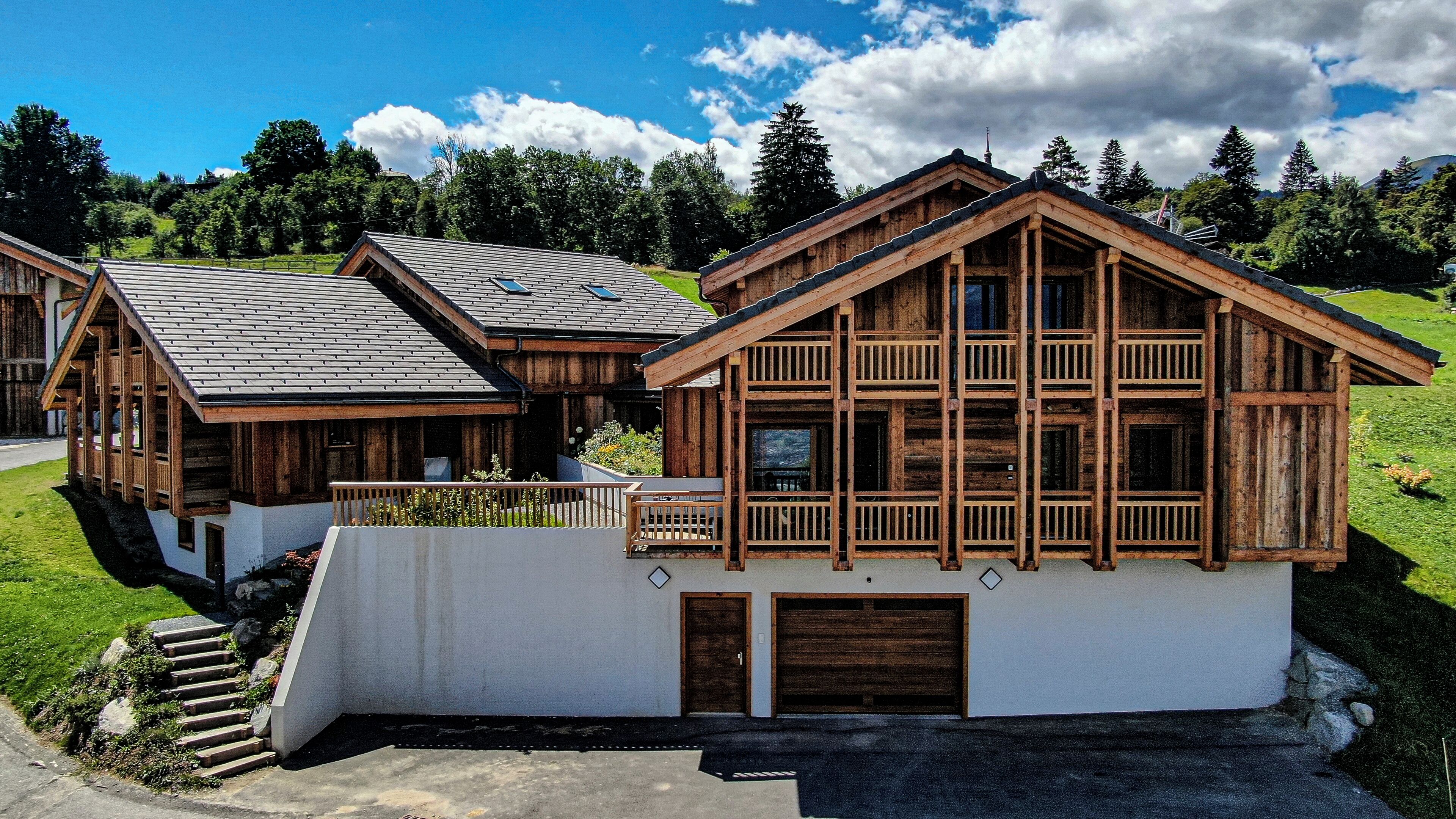 Un chalet en bois doté d’un balcon, d’un garage et d’un escalier menant à l’entrée.
