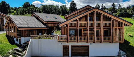 Un chalet en bois doté d’un balcon, d’un garage et d’un escalier menant à l’entrée.