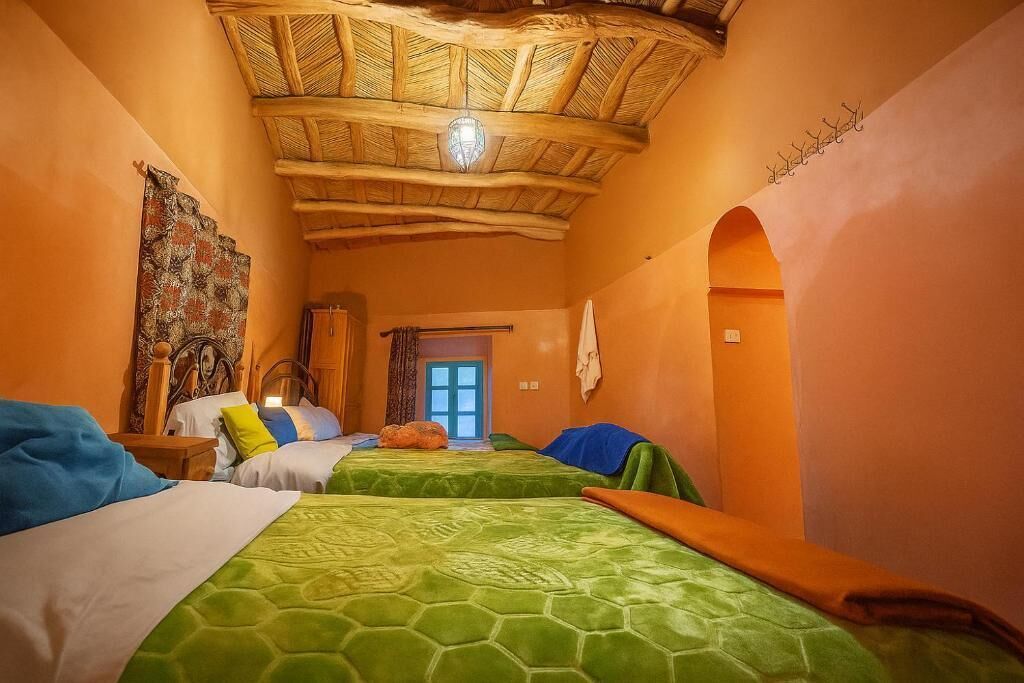 A room with two beds, a wooden ceiling, and a window.