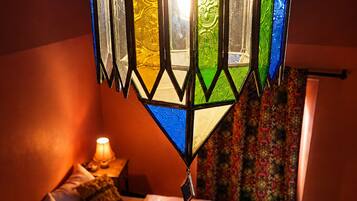 Een kamer met een bed, nachtkastje, lamp en hanglamp.