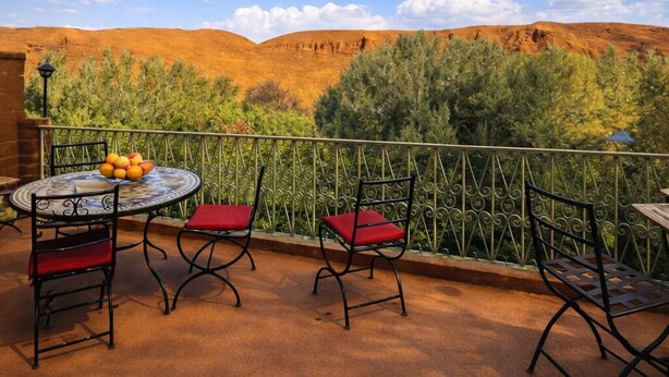 A terrace with a table and chairs, a view of hills, and a clear sky. - dar moha dades (Ait Sedrate Jbel El Soufla)