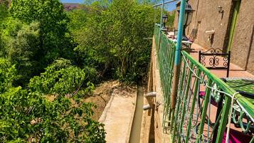 A balcony with a view of a garden and a building with a green door.