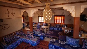 A traditional interior with wooden beams, patterned cushions, and a hanging light fixture. - dar moha dades (Ait Sedrate Jbel El Soufla)
