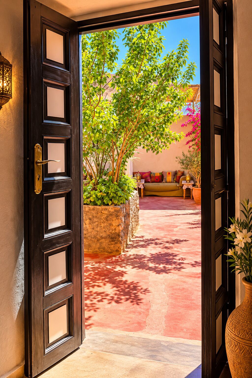 An open door leading to a courtyard with a sofa and potted plants.