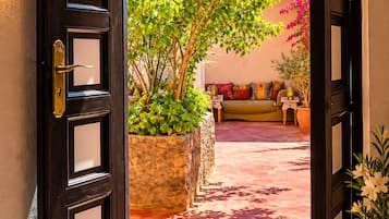 An open door leading to a courtyard with a sofa and potted plants.