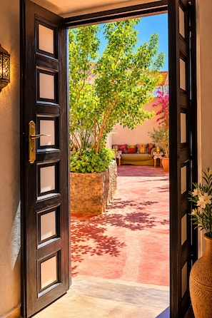 Puerta abierta que da a un patio con un sofá y plantas en macetas.