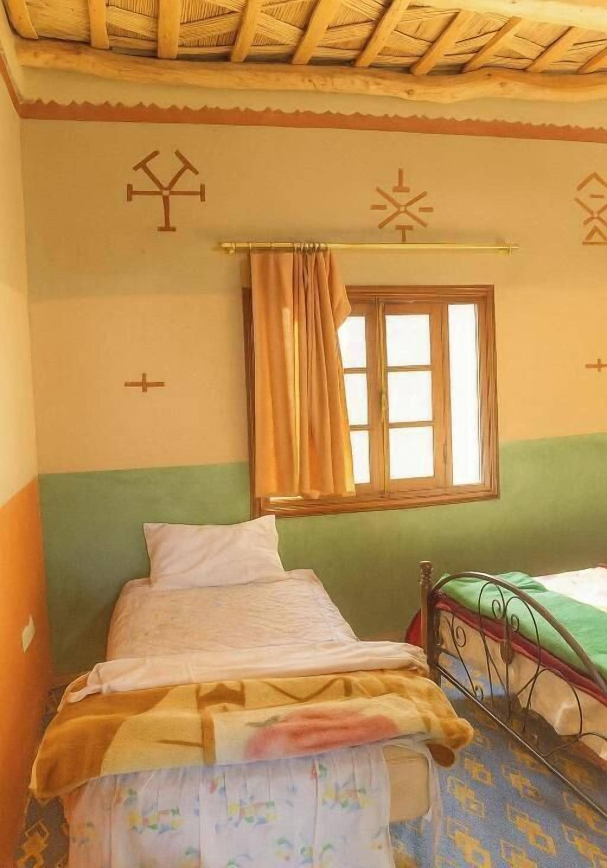A room with two beds, a window with curtains, and wall decorations.