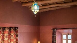 A room with two beds, a hanging lantern, and a window with curtains. - dar moha dades (Ait Sedrate Jbel El Soufla)