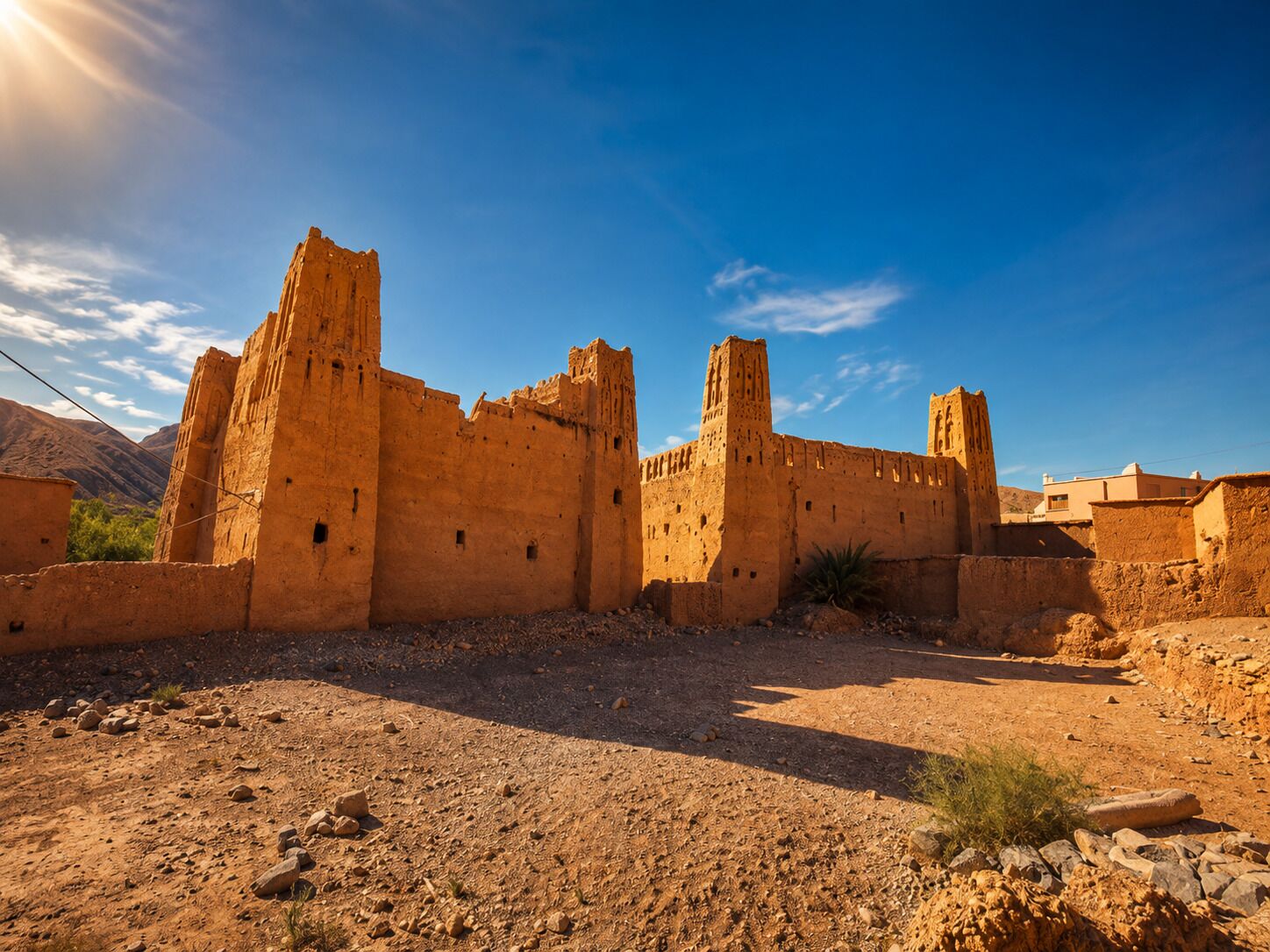 Una antigua construcción fortificada con múltiples torres y muros, rodeada por un paisaje árido y rocoso.