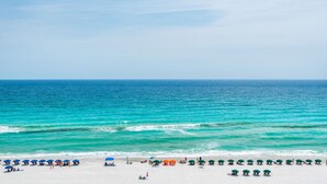Une plage bordée d’une rangée de parasols et de chaises le long du rivage.
