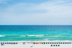 Ein Strand mit einer Reihe von Sonnenschirmen und Liegen entlang der Küste.