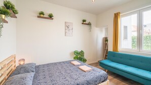 Ett sovrum med en säng, en blå soffa och ett fönster med gardiner.