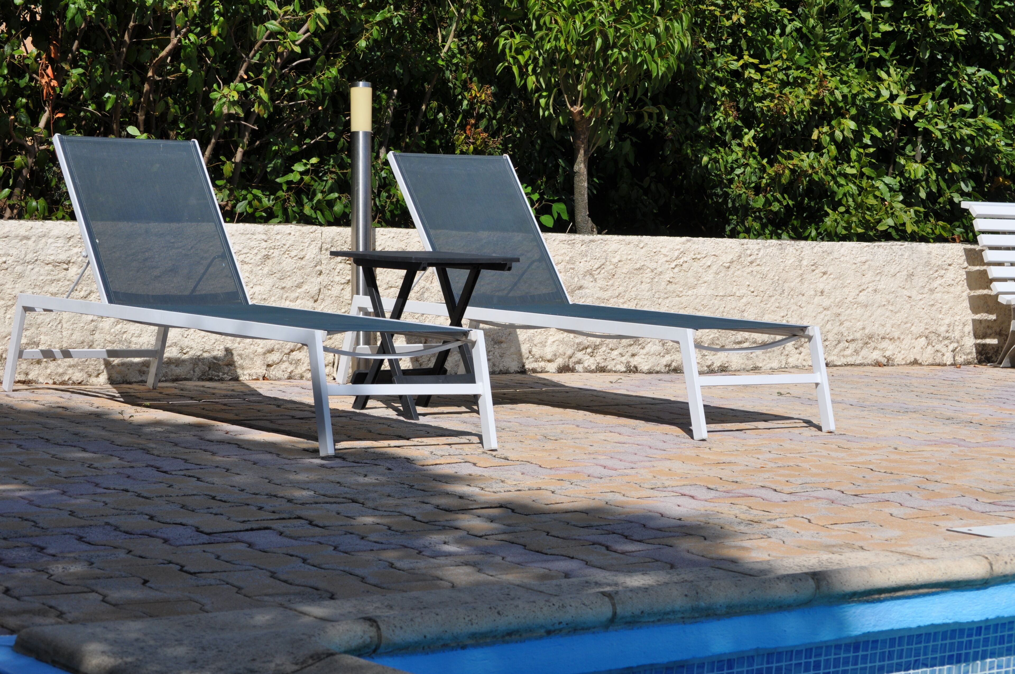 Ein Poolbereich mit zwei Liegestühlen, einem kleinen Tisch und einem Pool.