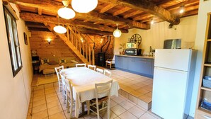 A rustic kitchen with a dining table, wooden beams, and a built-in oven.