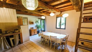 A kitchen with a dining table, wooden cabinets, and a hanging light fixture.