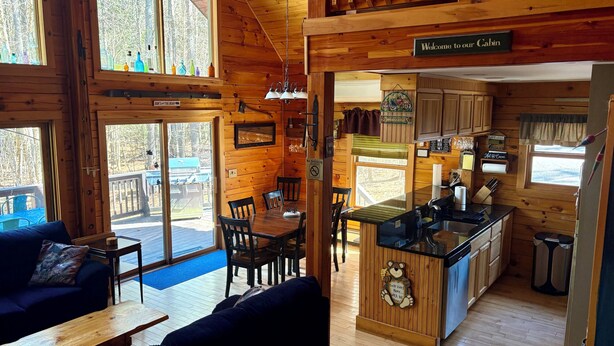 Interior de una cabaña con comedor, cocina y un cartel de bienvenida a los huéspedes.