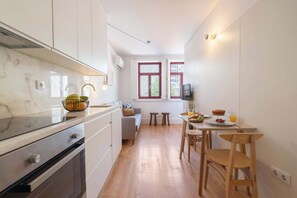 Eine kleine Küche mit Marmorarbeitsplatte, Holzschränken, einem Esstisch mit Stühlen und einer Sitzecke mit einer Couch.