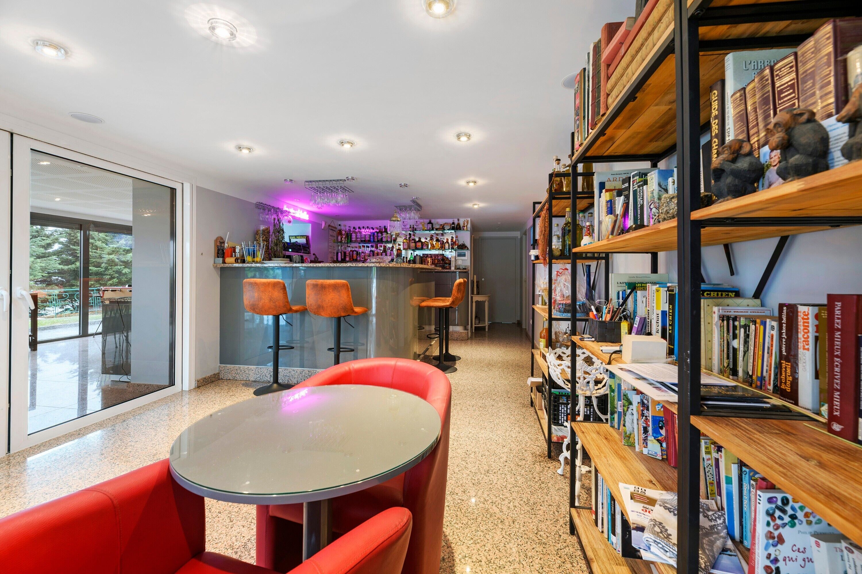 A modern interior with a bar area, seating, and a bookshelf.