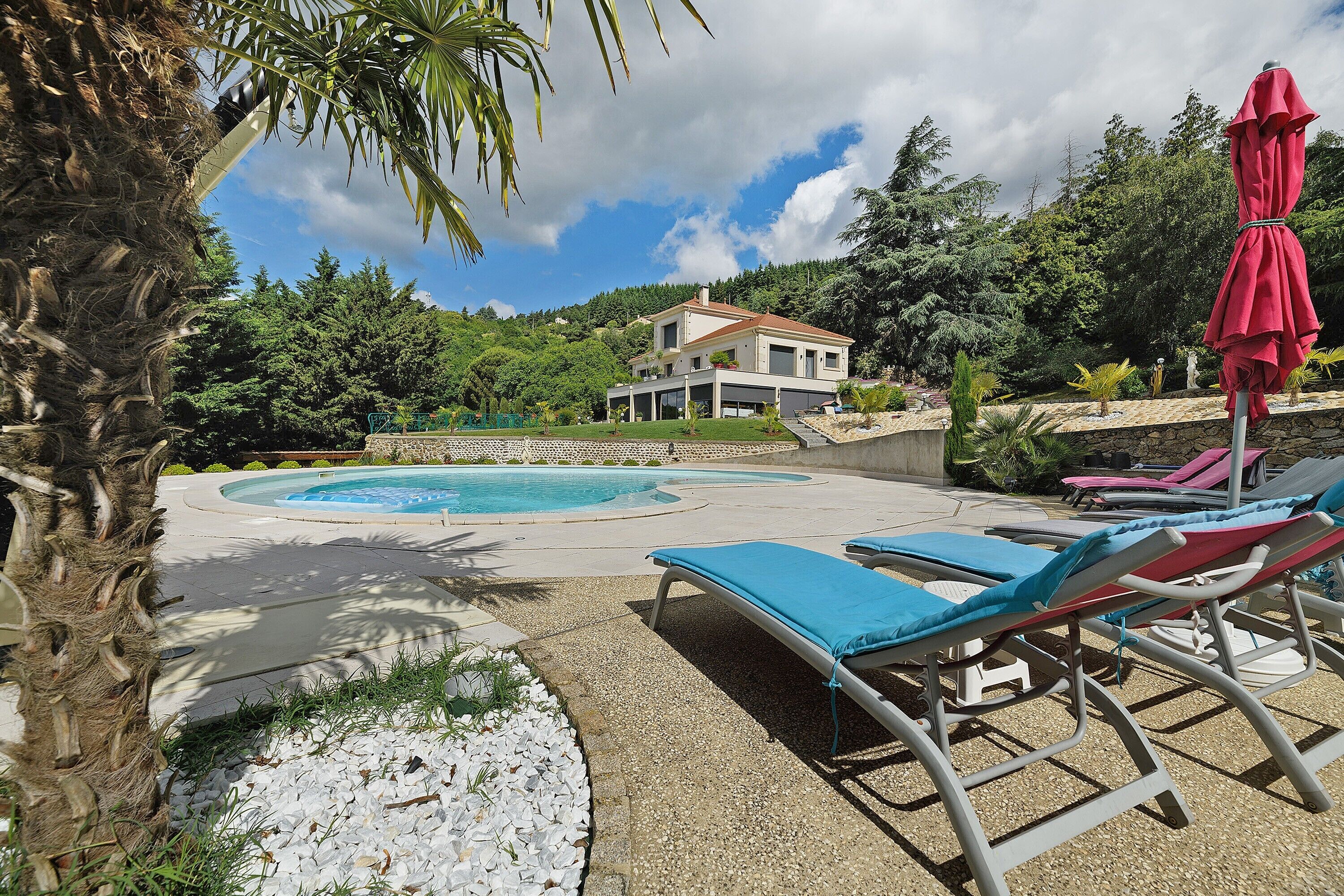 Une piscine entourée de chaises longues, avec une maison en arrière-plan.
