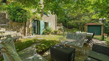 A stone building with a green door, outdoor furniture, and a garden area.