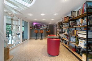 Un interno moderno con un'area bar, scaffali e un pouf rosso.