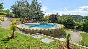 A landscaped pool area with lounge chairs, a stone pathway, and surrounding greenery.