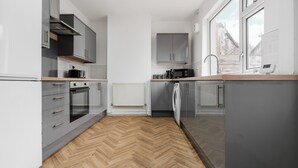 Una cocina moderna con armarios grises, suelo con diseño espiga y un ventanal que proporciona luz natural.