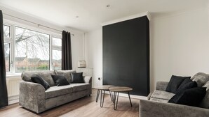 Una sala de estar moderna con un sofá gris, una mesita redonda y una pared de acento negra grande.