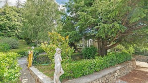 Ein Garten mit einer Statue, einer Steinmauer und einem Weg.
