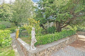 A garden with a statue, stone wall, and pathway.