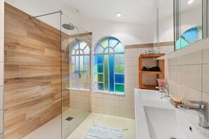 A modern bathroom with a glass shower enclosure, a large sink, and a vanity with a mirror.