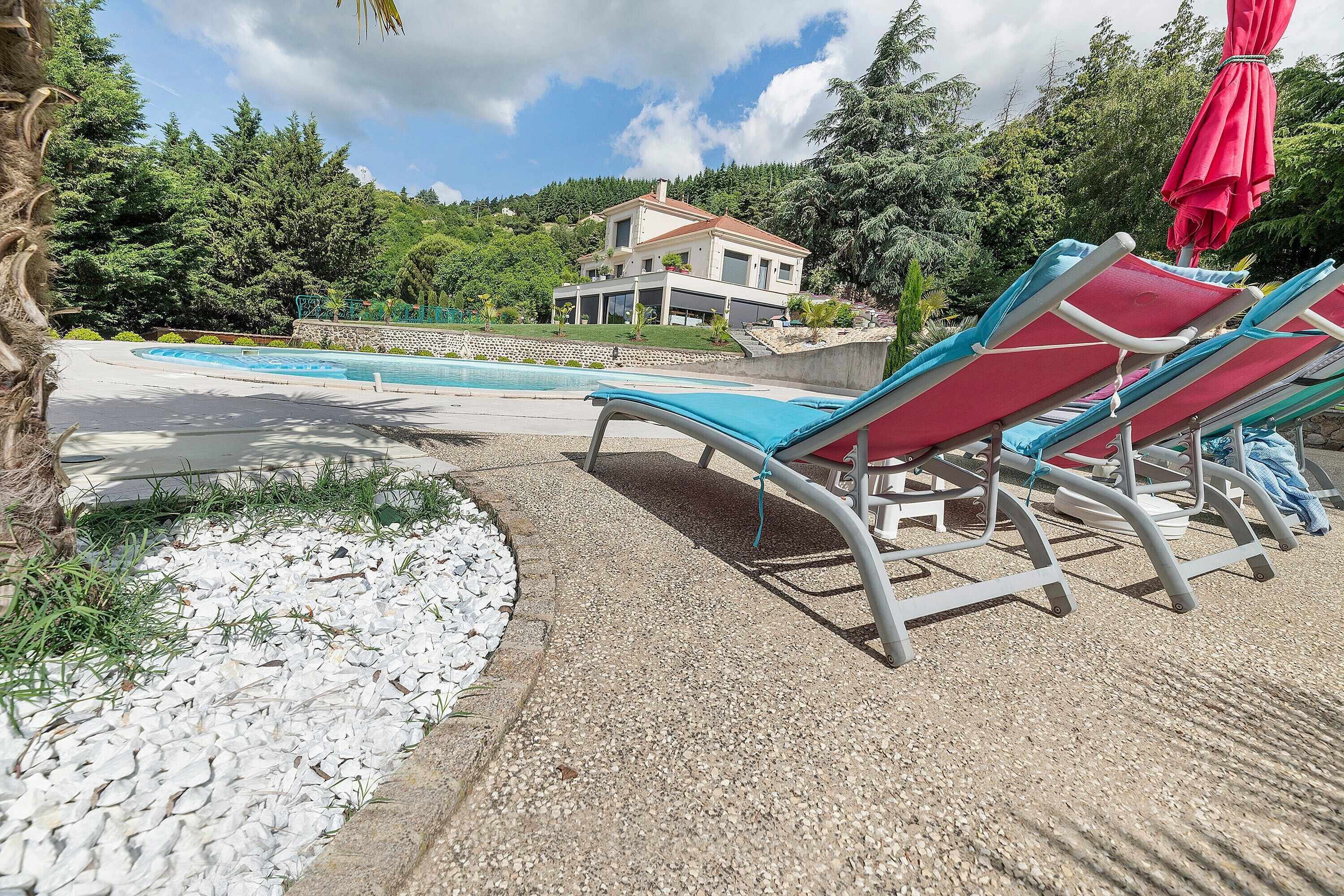 Un espace piscine avec des chaises longues et une maison moderne en arrière-plan.