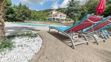 Un espace piscine avec des chaises longues et une maison moderne en arrière-plan.