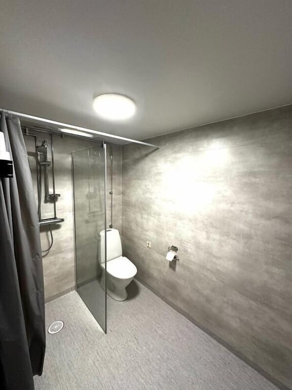 Une salle de bain moderne avec une douche à parois de verre, des toilettes et un porte-serviettes.