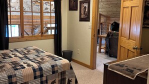 A bedroom with a wooden ceiling, a bed with a quilt, a window with curtains, and a door leading to another room. - Cozy lake cabin in Crosslake with a fireplace, perfect for relaxing getaways. (Crosslake)