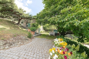 A paved pathway leading to a house with a garden. - Holiday Home 'Bergerie at Domaine de Cabu' with Mountain View, Shared Pool and Wi-Fi (Saint-Victor)