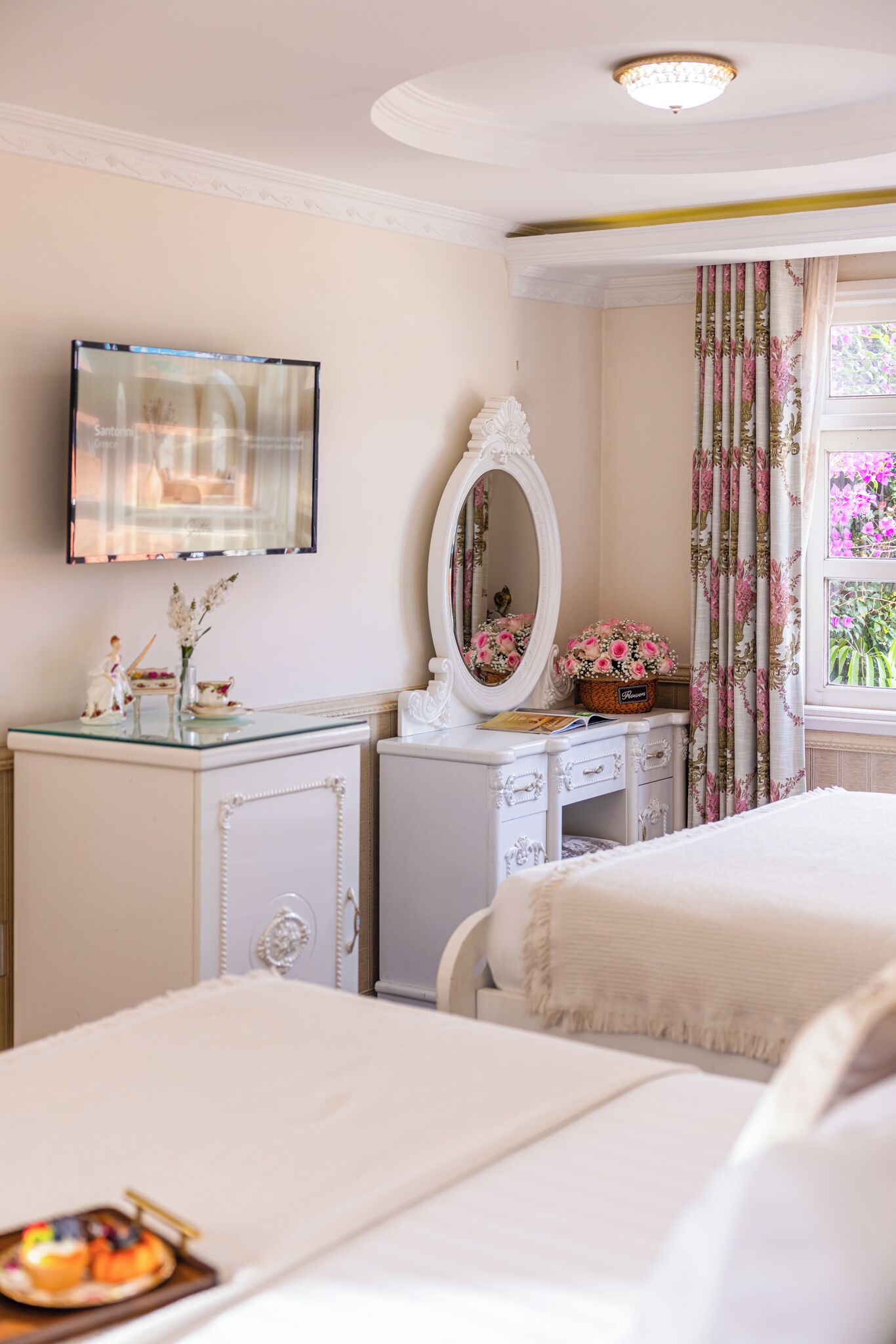 A bedroom with two beds, a dresser, a mirror, and a television on the wall.